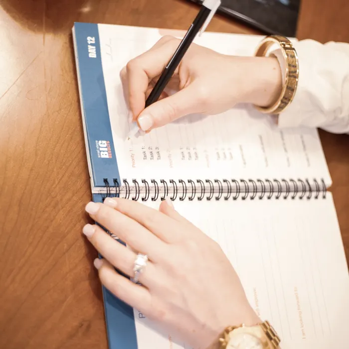 Mão escrevendo o plano alimentar em um caderno